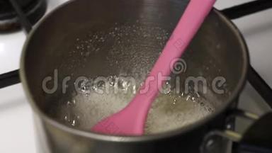 糖浆在<strong>炖锅</strong>里煮，准备棉花糖。 可见的厚泡沫。 一个人把糖浆混合，这样它就不会燃烧